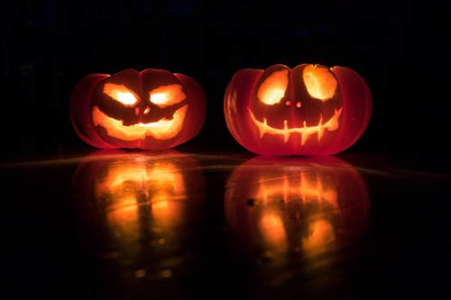 Two lit pumpkin lanterns in the dark