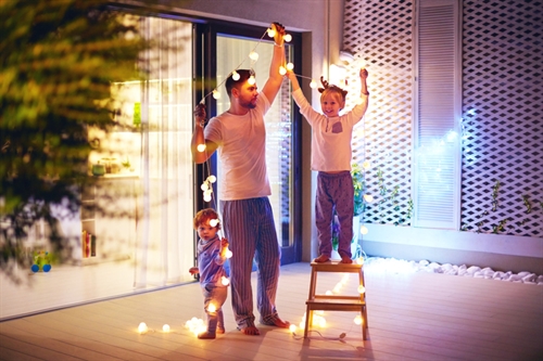 Dad and two boys taking down Christmas lights in a large modern room