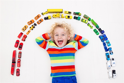A child surrounded by small brightly coloured toys