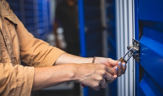 A woman locking her storage unit with a padlock and key A woman locking her storage unit with a padlock and key