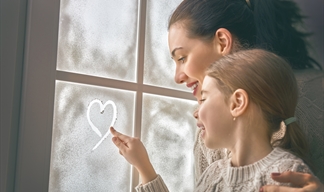 girl drawing a heart on frozen window with her mum in a warm December family scene. girl drawing a heart on frozen window with her mum in a warm December family scene.