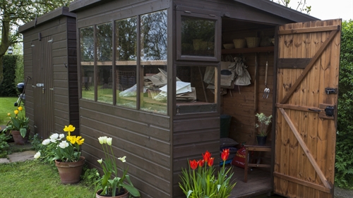 A classy brown shed with windows and a welcoming open door A classy brown shed with windows and a welcoming open door