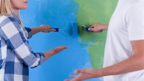 A man and a woman discussing whether to paint a wall blue or green A man and a woman discussing whether to paint a wall blue or green